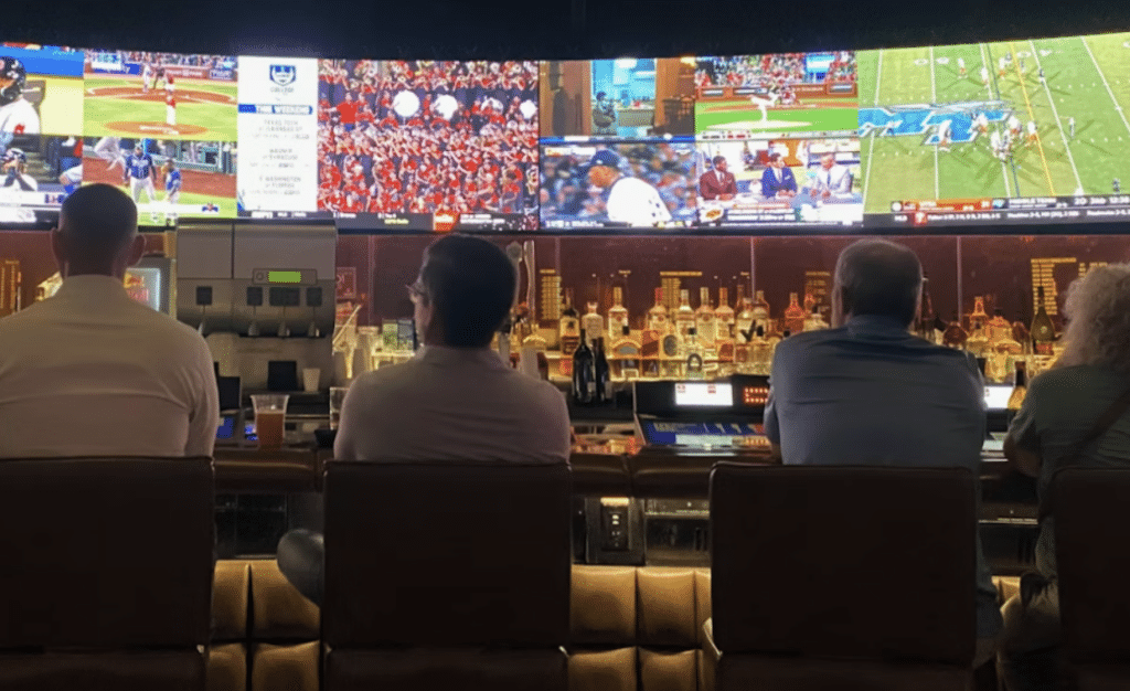 People sitting at a bar watching multiple sports games on large screens
